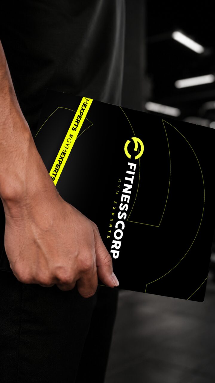 El manual de marca de Fitnesscorp en mano, con la cinta #GymExperts